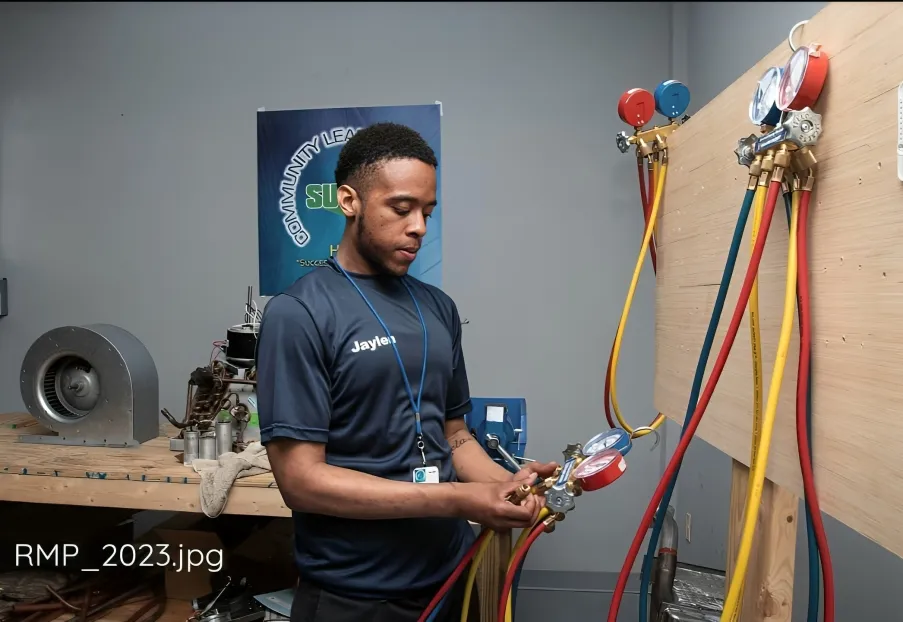 Student working on HVAC system with gauges and tubing, Su’Coy CLC training.