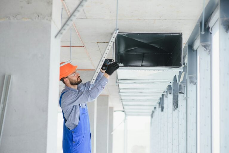 Technician inspecting rectangular commercial supply ductwork overhead